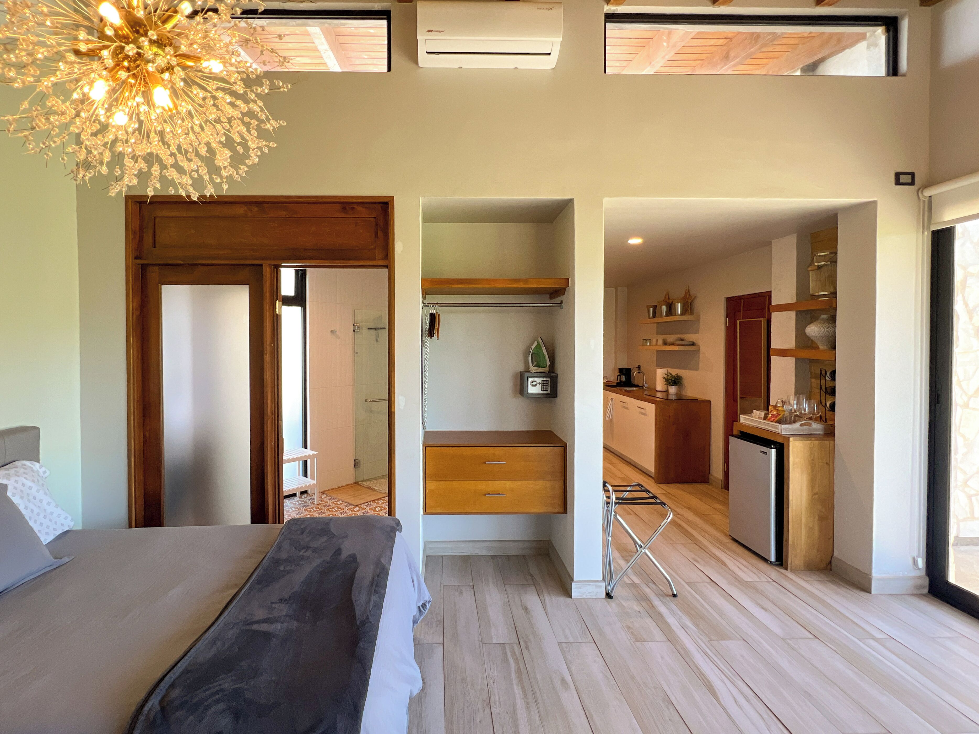 A modern bedroom with a large bed, a walk-in closet, and a kitchenette.