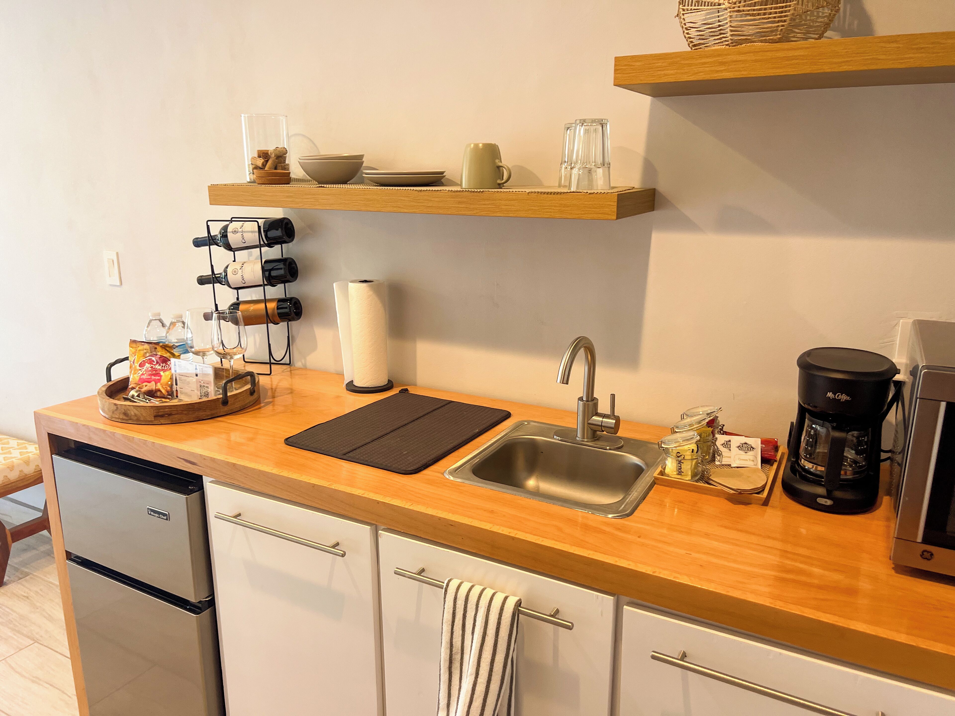 Une cuisine moderne dotée d’un évier en acier inoxydable, d’un plan de travail en bois et d’une machine à café.