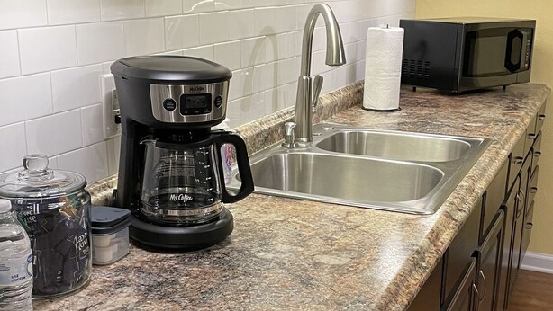 A kitchen with granite countertops, stainless steel appliances, and wooden cabinets. - O2 Suites Houma (Houma)