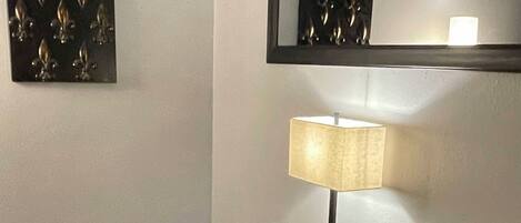 A room with a wooden desk, a leather chair, a lamp, and a wall-mounted mirror.