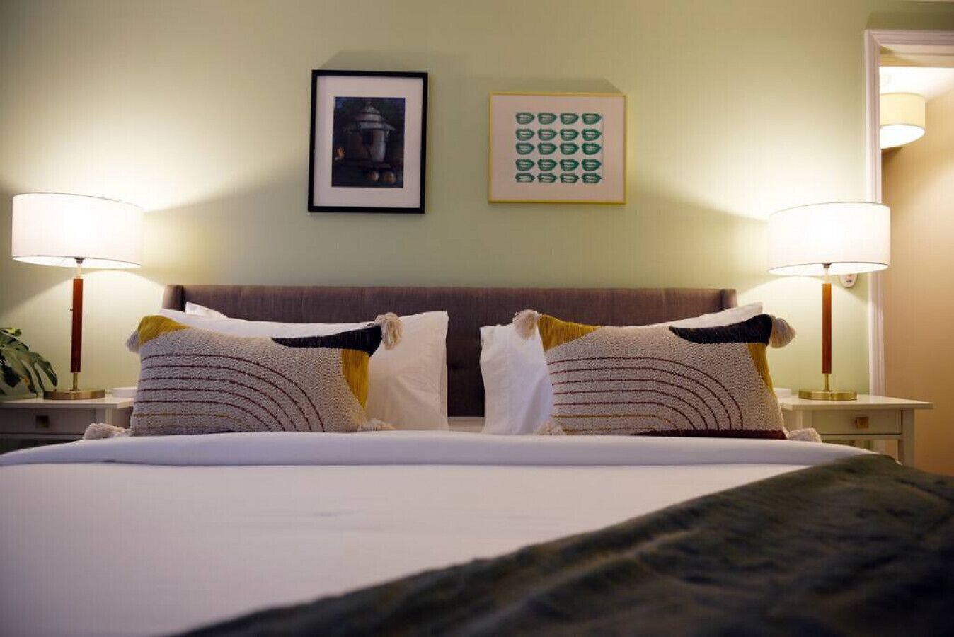 Hotelkamer met een groot bed, twee bedlampen, een ingelijste foto boven het bed en een wandklok.