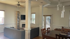 A spacious living room with a fireplace, a dining area with a wooden table and chairs, and a built-in bookshelf.