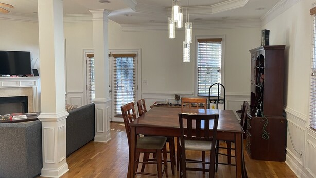A dining area with a wooden table and chairs, a fireplace, and a television on a stand.