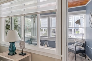 Enjoy a view of the outside from the large window, featuring a table with a lamp and decorative fan.