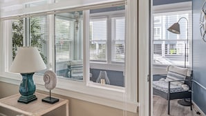 A room with a view of the outside, a table with a lamp, and a chair with a patterned cushion. - Coastal Condo Close to Beach & Entertainment (Rehoboth Beach)