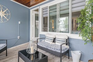Relax in a serene space with a wicker sofa, glass coffee table, and a potted plant.