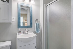 Bathroom features a sink, mirror, and shower area with a glass door.