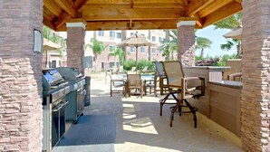 Un patio al aire libre con zona de barbacoa, muros de piedra y mobiliario exterior.