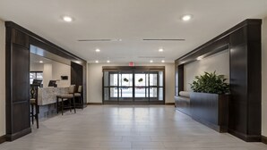 A spacious lobby with a reception desk, seating area, and a large glass door entrance. - Flexible 1-Bedroom Suite w/ Full Kitchen, KS (Overland Park)