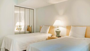 Une chambre d’hôtel avec deux lits, un miroir, des lampes de chevet et une table de chevet.