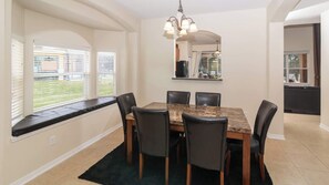 A dining area with a marble table, black chairs, and a chandelier.
