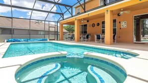 A swimming pool with a hot tub, surrounded by lounge chairs and a covered patio area. - Ohana House Fun in the Sun (Davenport)
