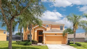 A two-story house with a garage, surrounded by well-maintained lawns and trees. - Ohana House Fun in the Sun (Davenport)