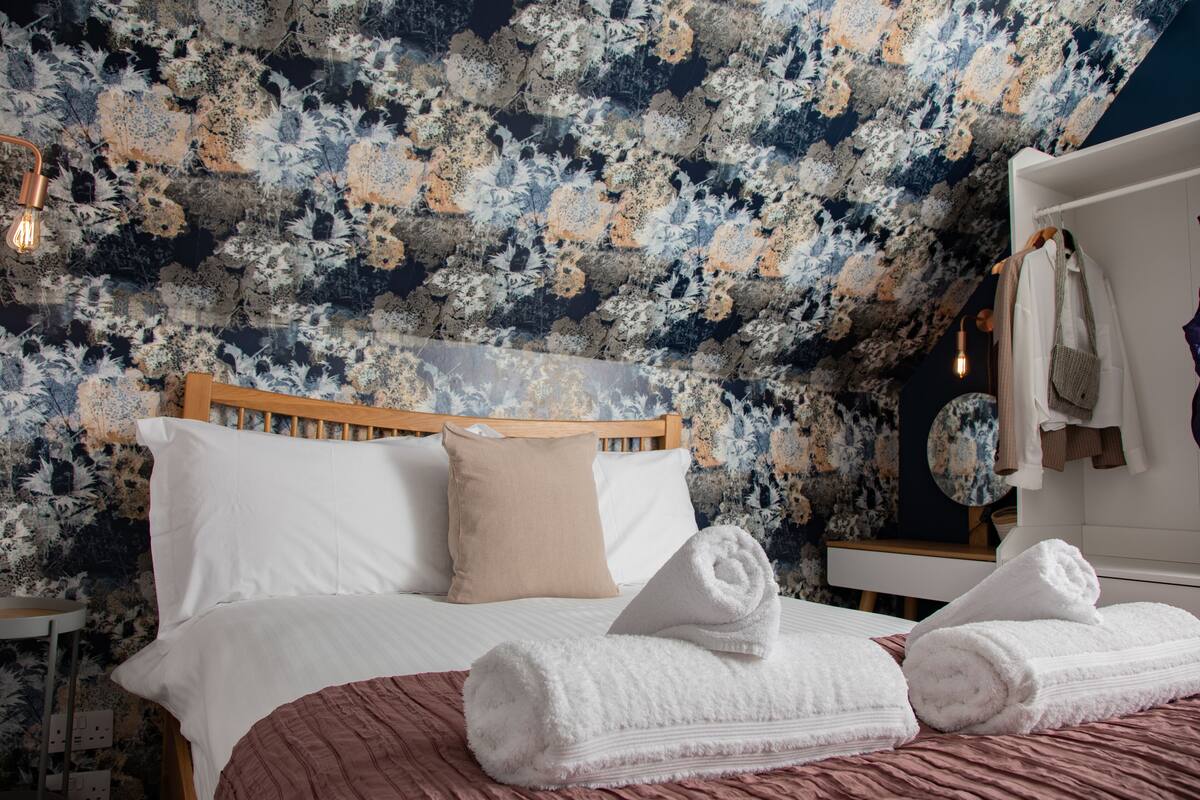 Une chambre à coucher avec un lit en bois, des oreillers blancs et beige, une couvre-lit rose et un plafond orné de motifs floraux.