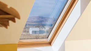 Un tragaluz con vistas a una casa y montañas.