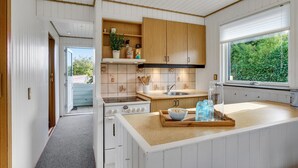A modern kitchen with white cabinetry, a wooden countertop, and a window with a view of greenery. - Nice home in Kerteminde with WiFi (Kerteminde)