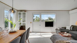 A modern living room with a wooden dining table set for four, a grey sofa, and a television mounted on the wall. - Nice home in Kerteminde with WiFi (Kerteminde)