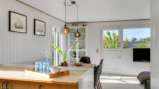 A modern kitchen with a wooden countertop, hanging pendant lights, and a view of the outdoors through a door. - Nice home in Kerteminde with WiFi (Kerteminde)