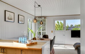 A modern kitchen with a wooden countertop, hanging pendant lights, and a view of the outdoors through a door. - Nice home in Kerteminde with WiFi (Kerteminde)