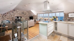 Een moderne keuken met een stenen muur, een groot raam en uitzicht op zee.