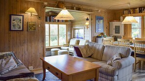 Une pièce chaleureuse avec un canapé, une table en bois et une bibliothèque remplie de livres.