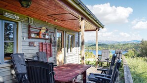Une cabane en bois dotée d’une véranda, d’un espace extérieur aménagé et offrant une vue panoramique sur les montagnes et un lac.