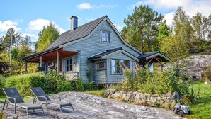 Une maison à deux étages avec un porche, un mur en pierre et un jardin.