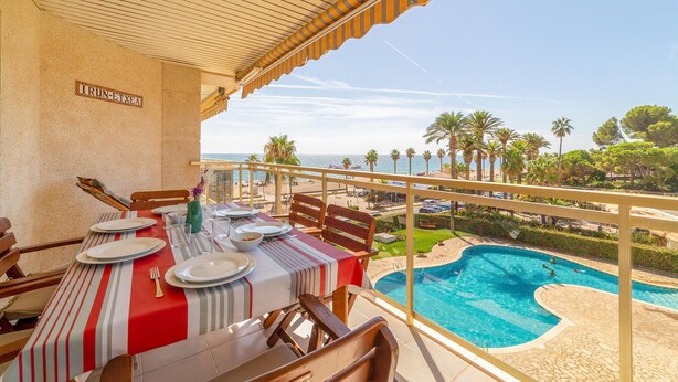 Ein Essbereich mit Tisch für vier Personen mit Blick auf einen Pool und Palmen.