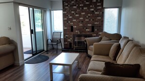 Un salon moderne comprenant un canapé, une table basse, une cheminée et une porte-fenêtre coulissante donnant sur un espace extérieur.