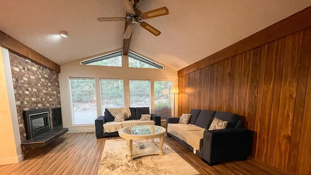 Un salon avec une cheminée, deux canapés, une table basse et un ventilateur de plafond.