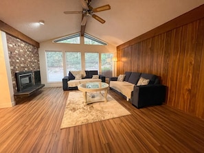 A living room with a fireplace, two sofas, a coffee table, and a ceiling fan. - Beautiful farm house with a ton of space and a Sauna . Family  friendly (Langley)