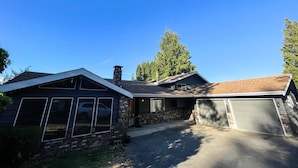 Une maison à deux étages avec un garage, une cheminée et une grande fenêtre.