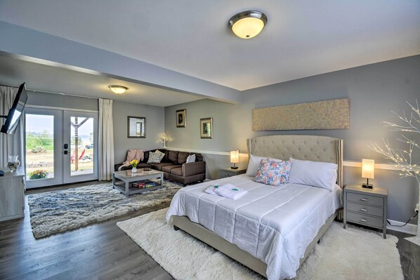 A bedroom with a large bed, a sofa, a desk, and a view of the outdoors. - Cozy Port Orchard Home w/ Grill & Fire Pit! (Port Orchard)