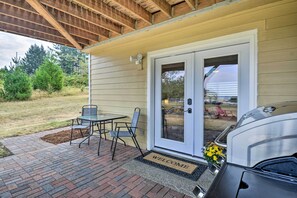 A covered patio with a table and chairs, a barbecue grill, and a welcome mat. - Cozy Port Orchard Home w/ Grill & Fire Pit! (Port Orchard)