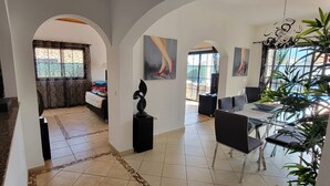 A spacious living area with a dining area, a kitchen, and a bedroom with a large window. - 4 bedroom LUXURY villa with AC, private heated pool, XBOX and all the amenities! (Castillo Caleta de Fuste)