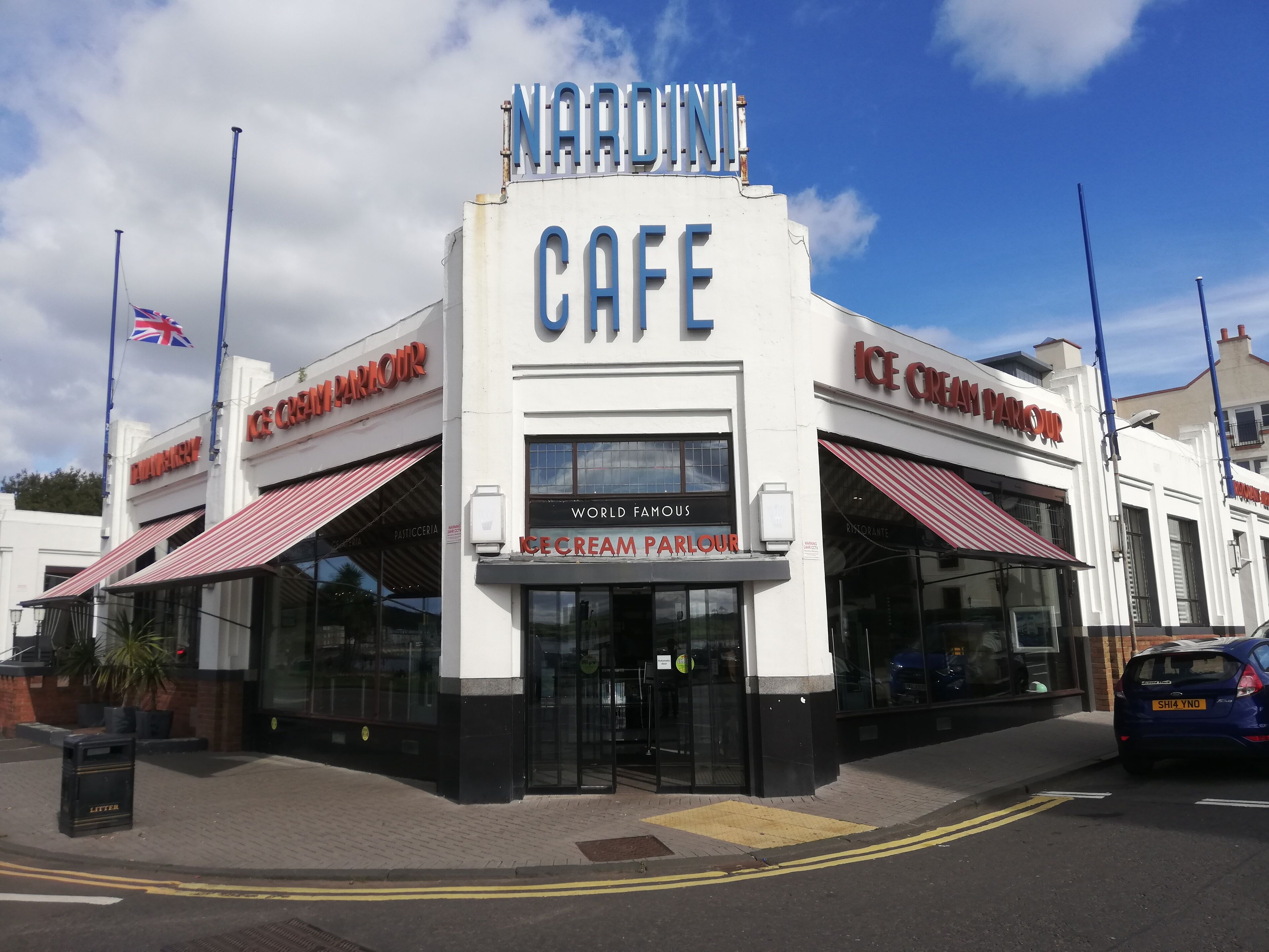 A building with a sign that reads 'NARDINI CAFE' and 'ICE CREAM PARLOUR' with a British flag.