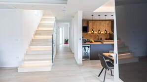 A modern kitchen with a central island, pendant lighting, and a staircase leading to another level. - Gorgeous home in Marina (Marina)