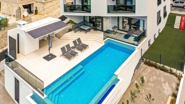 A modern building with a rooftop swimming pool, outdoor seating, and a stone facade. - Gorgeous home in Marina (Marina)