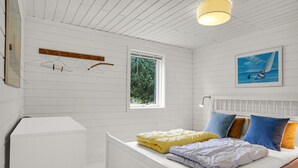 Een slaapkamer met een bed, een raam, een radiator en een schilderij aan de muur.