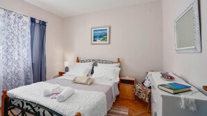 A neatly made bed with white linens, a bedside table with a lamp, a framed picture on the wall, and a mirror on the wall. - Gorgeous apartment in Kanica with WiFi (Kanica)