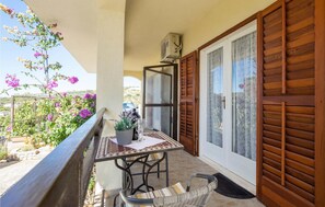 Ein Balkon mit Tisch und Stühlen, einem Blumentopf und Blick auf die umliegende Landschaft.