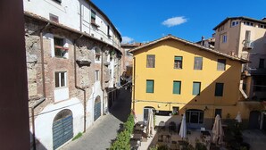 A narrow street with buildings on either side, including a yellow building with a sign that reads "Hotel & Restaurant". - Lovely apartment for 5 people with WIFI, A/C, TV and panoramic view (Lucca)
