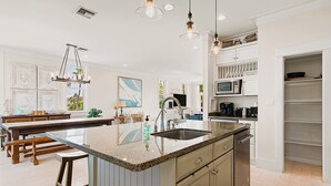 A modern kitchen with a central island, bar stools, a microwave, and a sink. - Lotus Villa-Beautiful Straw paths through the pretty dunes. Look out tower! (South Padre Island)