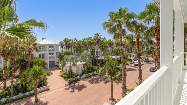A multi-story hotel with a central courtyard surrounded by palm trees and a parking area. - Lotus Villa-Beautiful Straw paths through the pretty dunes. Look out tower! (South Padre Island)
