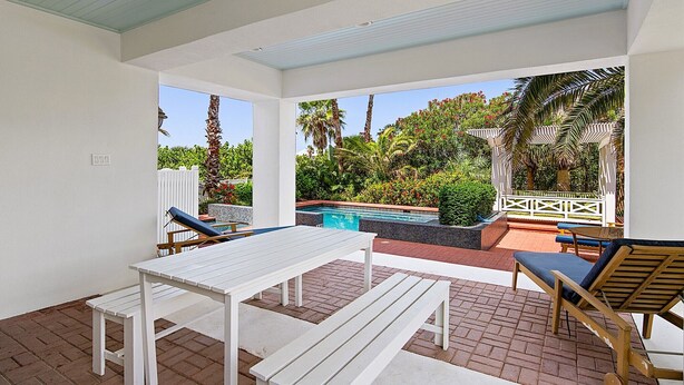 Un patio con piscina, mobiliario exterior y vistas a un jardín exuberante.