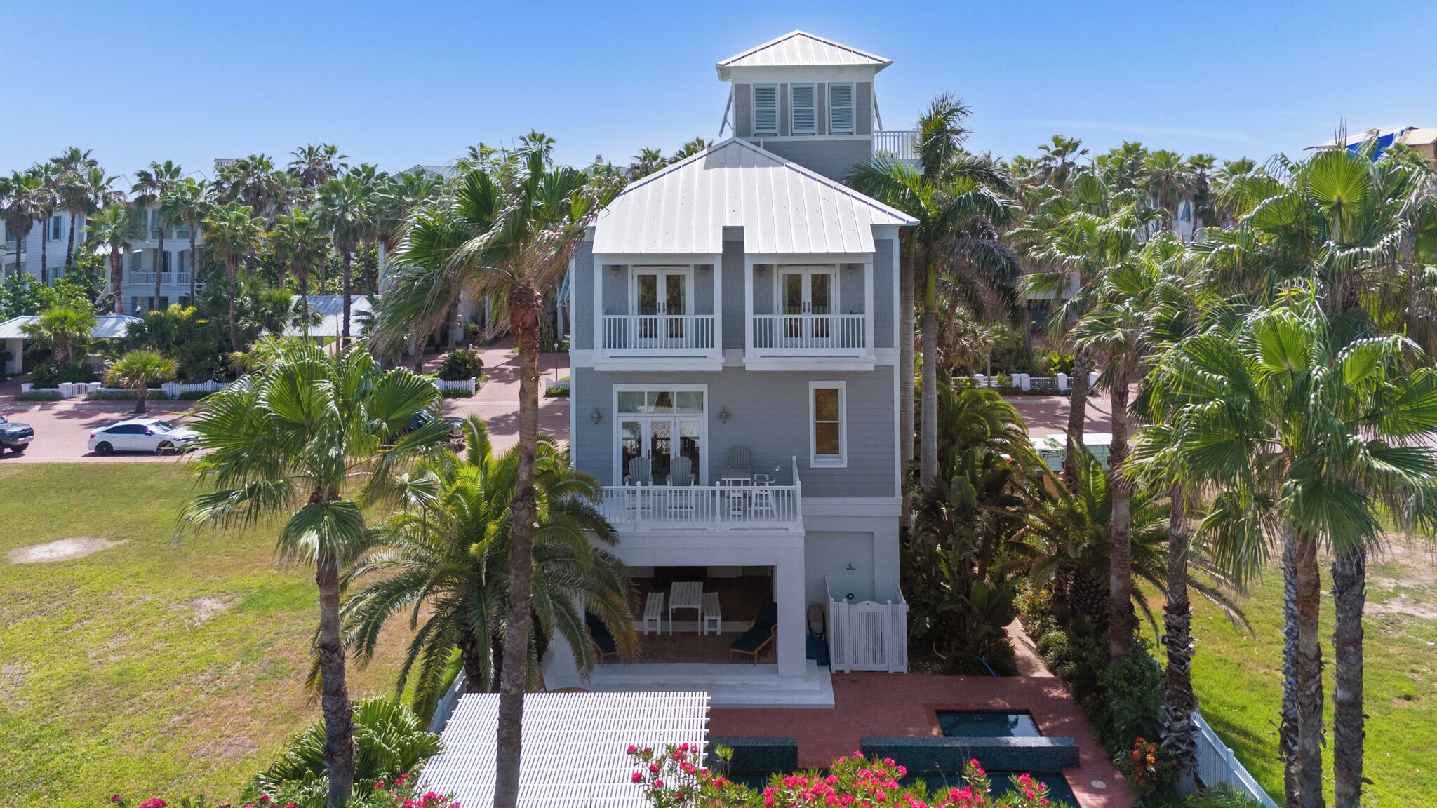 A two-story building with a balcony, surrounded by palm trees.