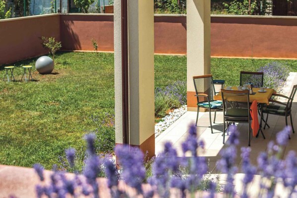 A patio with a table and chairs, a small garden, and a spherical object.