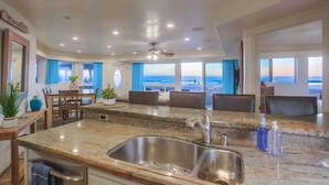Una cucina moderna con una grande isola, lavello in acciaio inossidabile e vista sull'oceano.