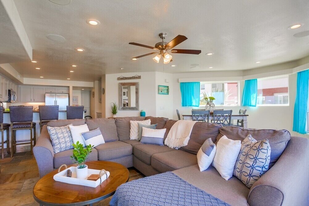 A modern living room with a sectional sofa, a coffee table, and a ceiling fan.