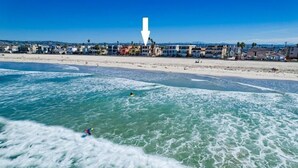 Una playa con aguas cristalinas y una hilera de casas coloridas al fondo.